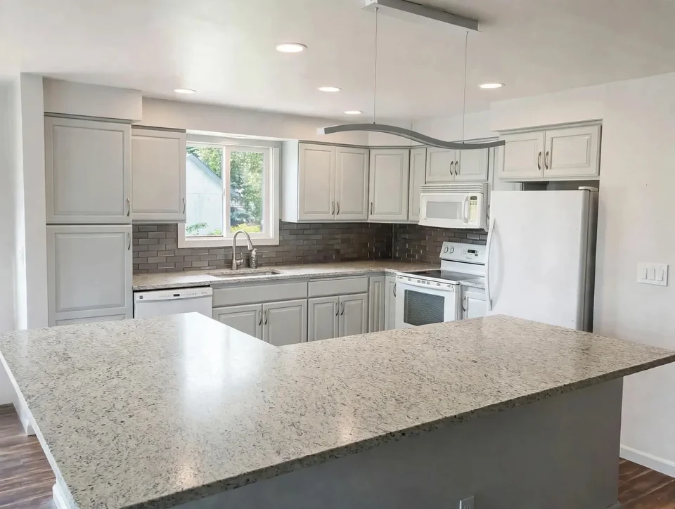 Small archival photo of a white kitchen island and pale cabinetry.