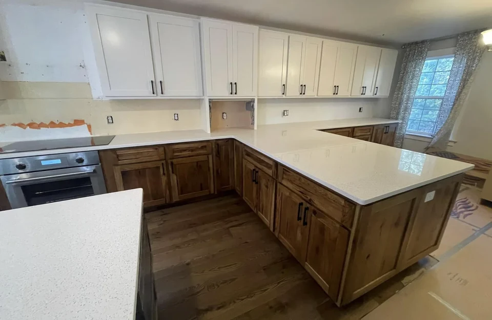 Kitchen installation in progress with white upper cabinets, a wood-grain island, and an unfinished backsplash.