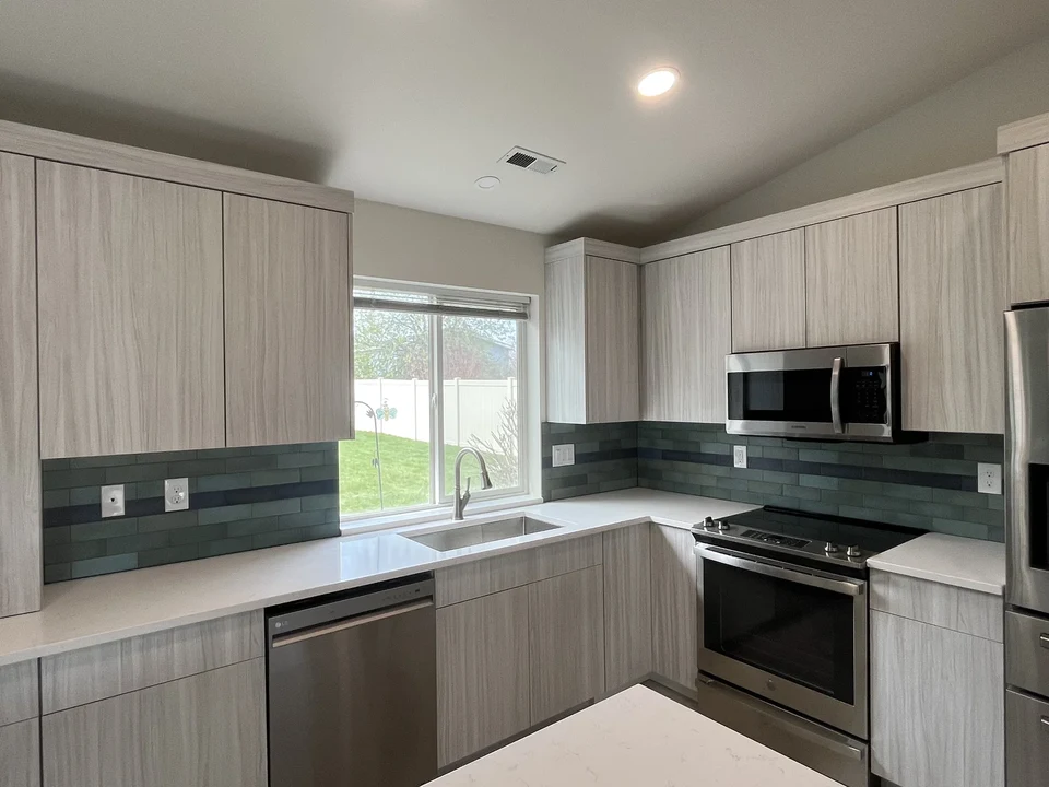 White kitchen cabinets around a window with dark countertops and a stainless steel range.