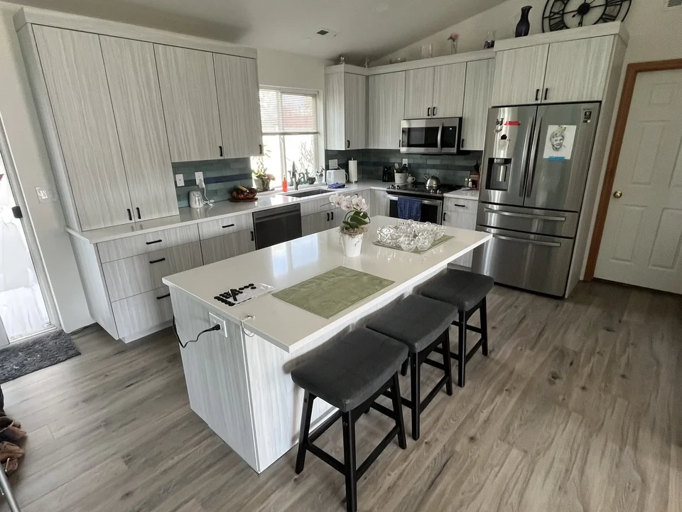 Bright kitchen with a white island, bar stools, and pale cabinetry.