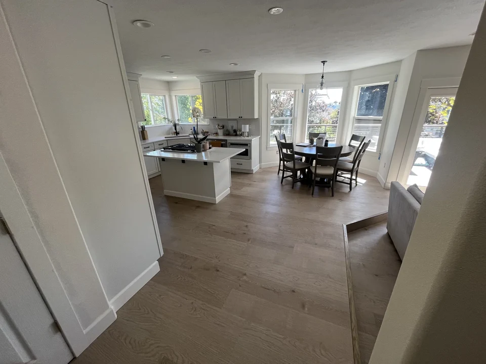 Open kitchen and dining area with light wood flooring and windows.
