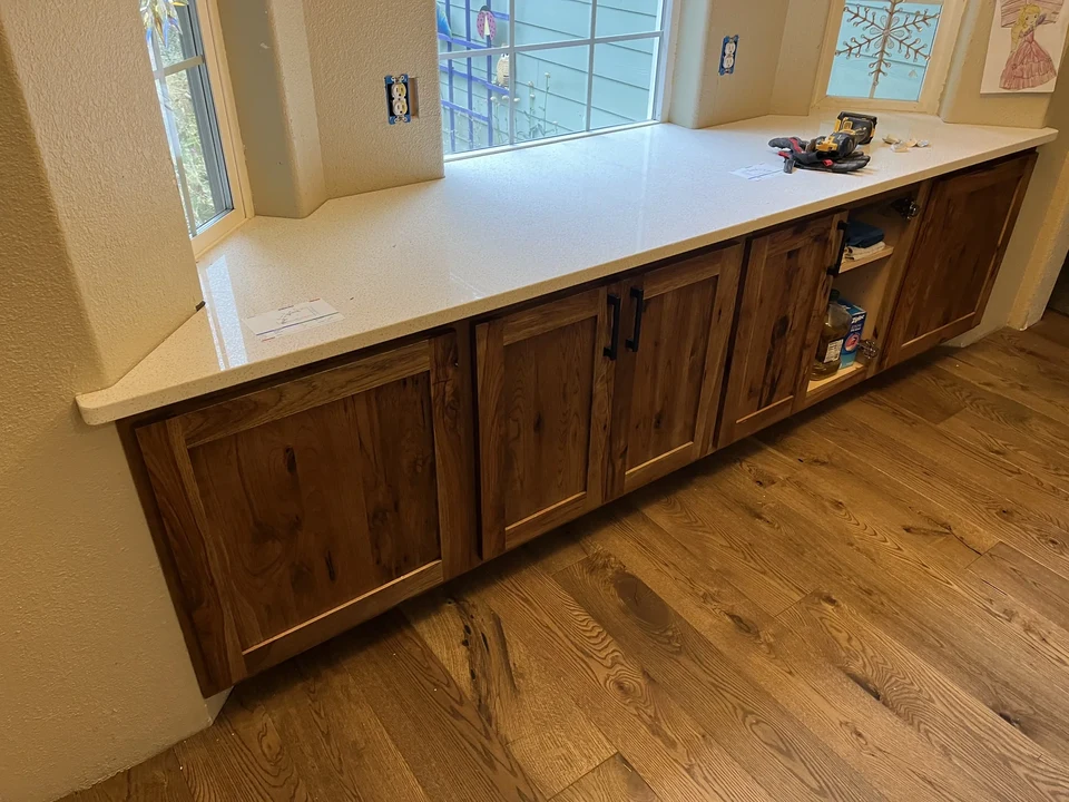 Long white countertop over natural wood lower cabinets in a bright kitchen.