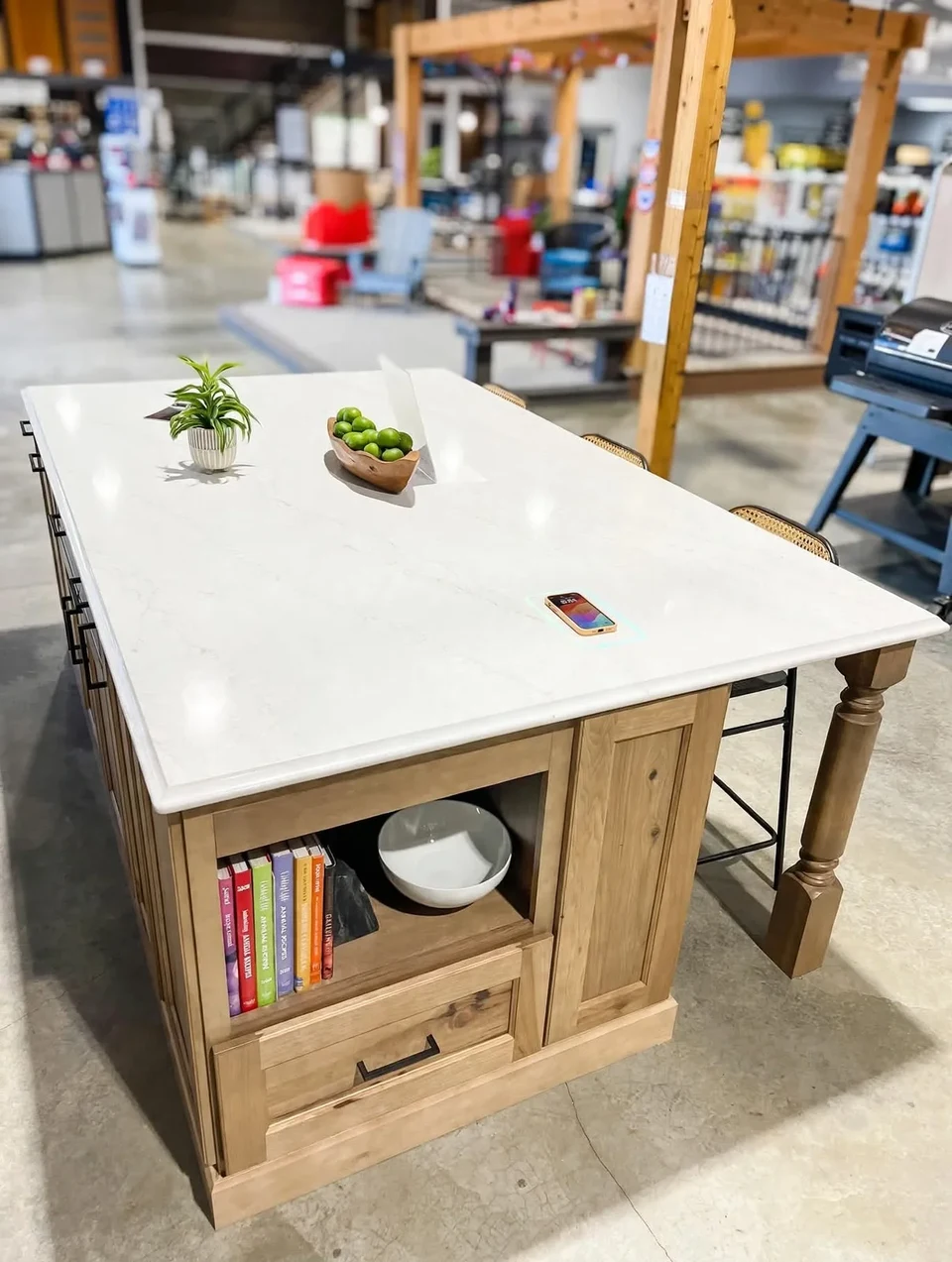 Wood kitchen island with a pale countertop, open shelving, and cabinet storage in a workshop.