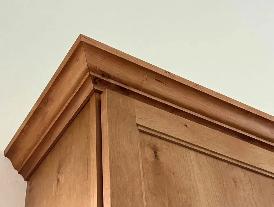 Close-up of natural wood cabinet doors and layered crown molding.