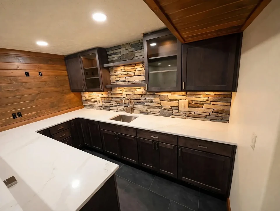 Kitchen with dark cabinetry, a pale countertop, textured backsplash, wood walls, and a wood ceiling.